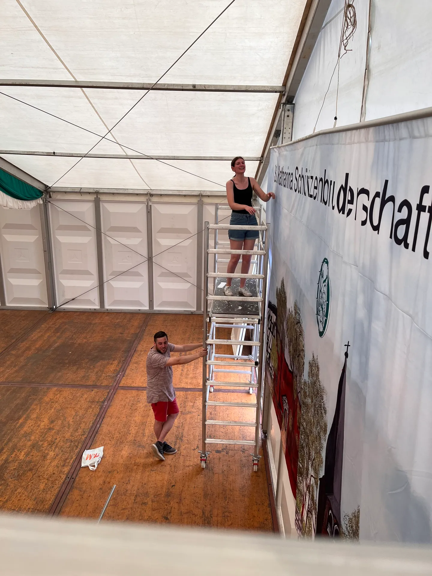Vereinsmitglied hängt das Vereins-Banner am Innenrahmen des Festzeltes auf