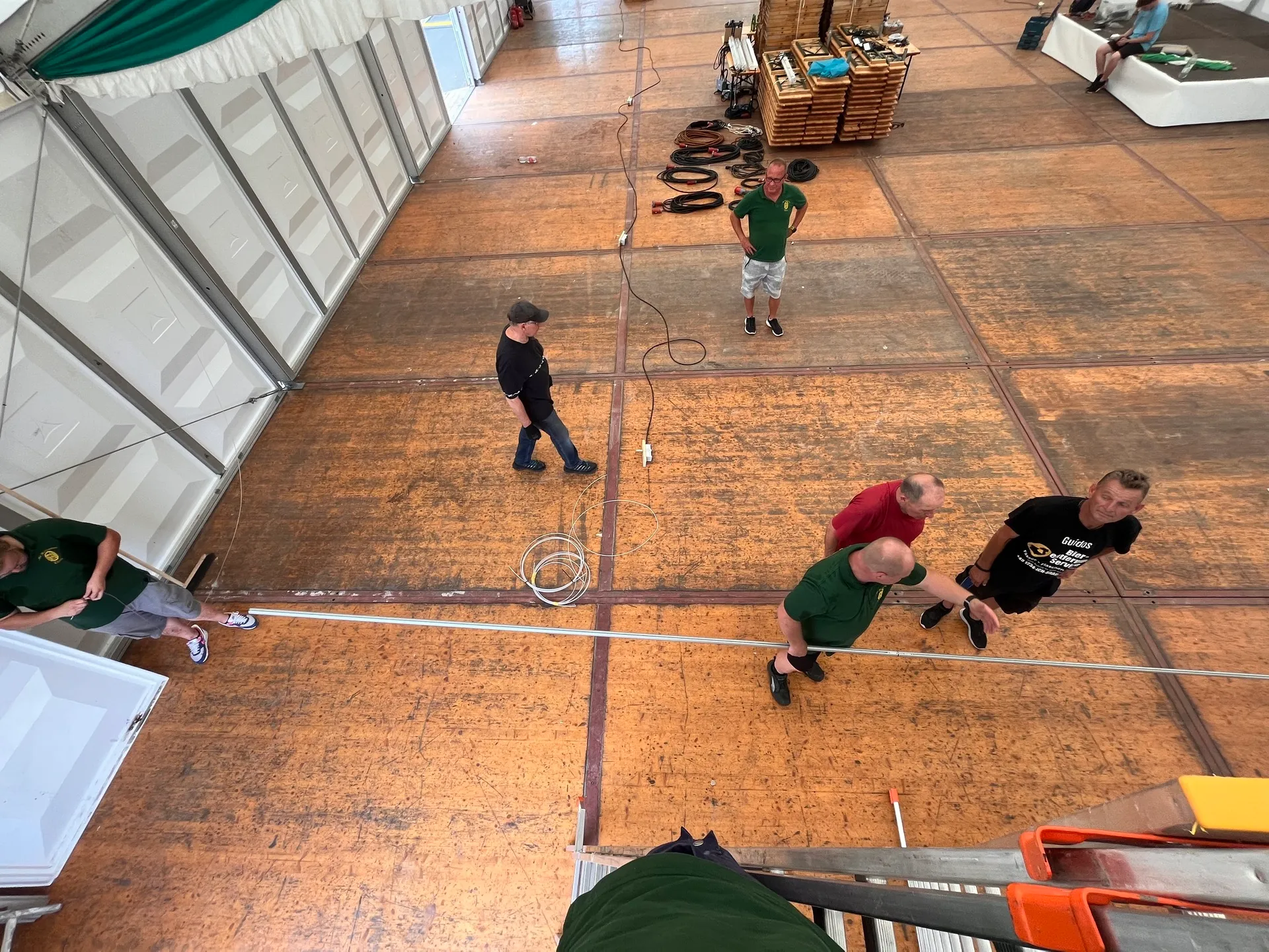 Helferteam beim Verlegen von Kabeln und Aufräumen des Festzelt-Holzbodens