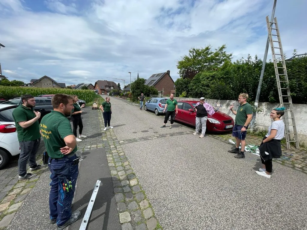 Vereinsmitglieder ziehen die Wimpelkette zwischen den Masten straff