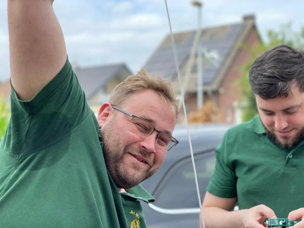 Helfer auf der Leiter beim Befestigen der Girlande am Laternenmast