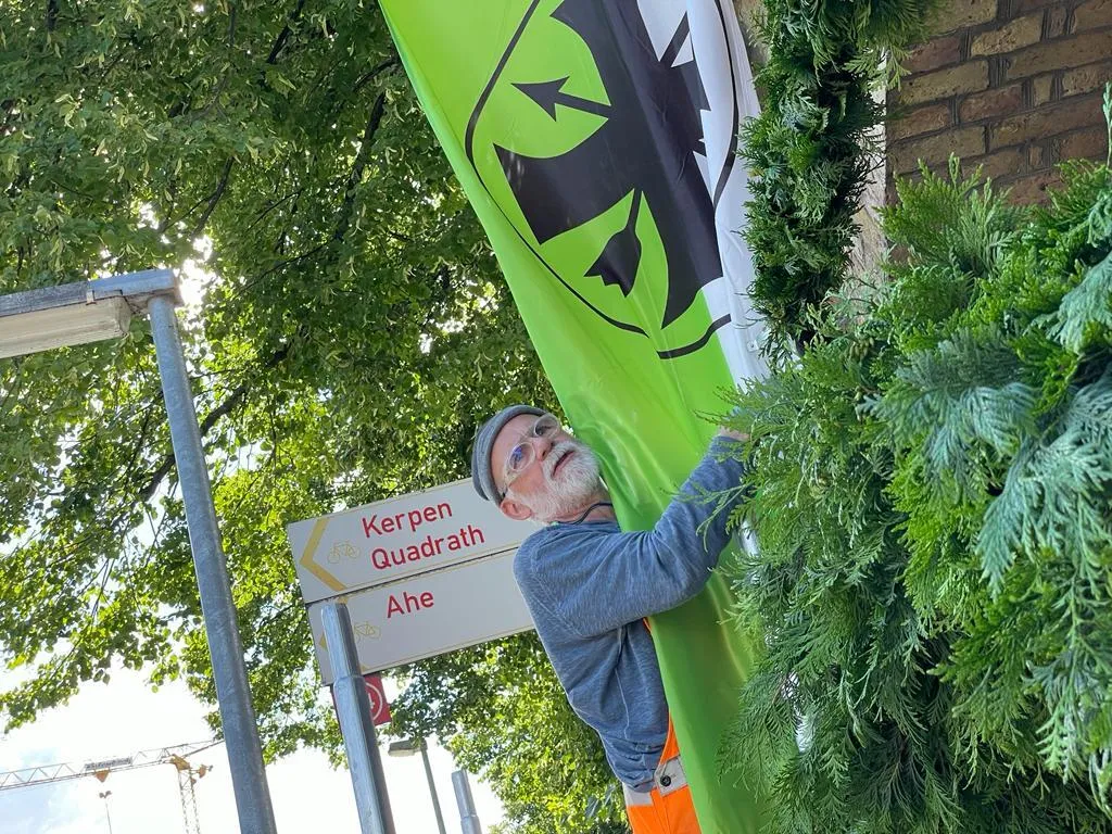 Helfer beim Schmücken des Königshauses, im Hintergrund Wimpelketten über der Straße