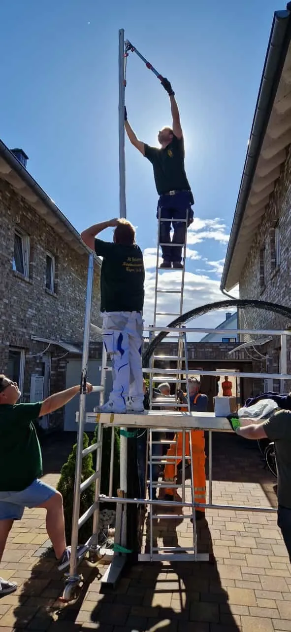Helfer bringen Tannenzweige am Tor-Bogen an