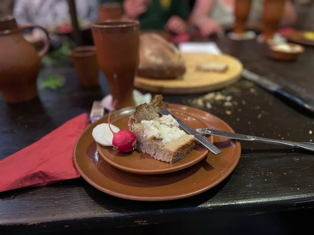 Mittelalterliches Gedeck: Brot mit Aufstrich, Rettich und Radieschen auf Tontellern