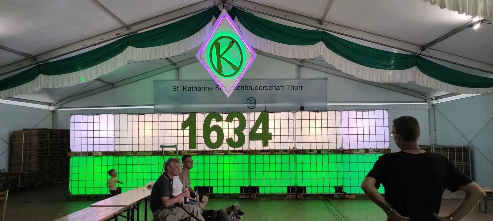 Festzelt mit beleuchtetem „K"-Wappen und „1634"-Schriftzug aus IBC-Containern am Vorabend des Festes
