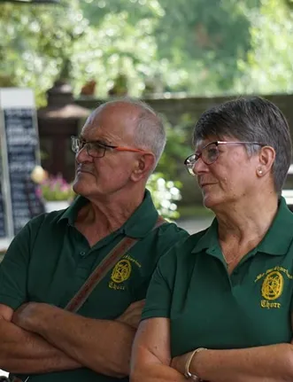 Zwei Mitglieder der St. Katharina Bruderschaft in grünen Vereins-Polos mit Wappen